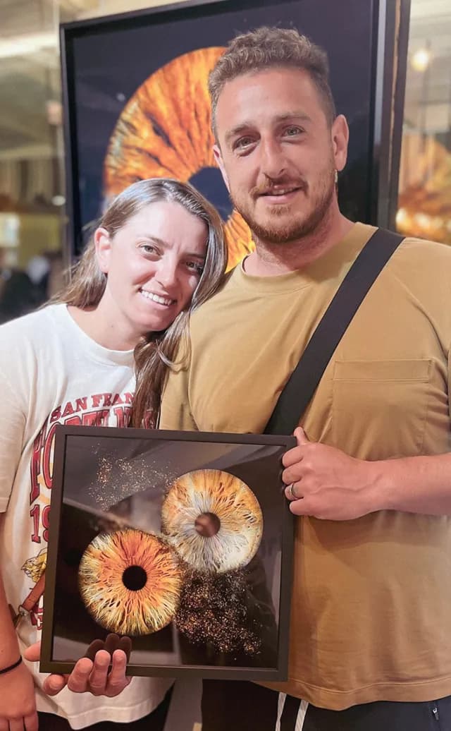 A couple holding their framed iris artwork